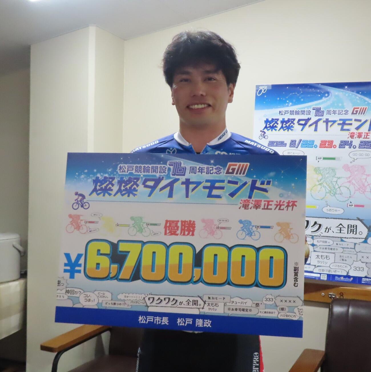 大会連覇を飾った岩本俊介が賞金ボードを掲げる