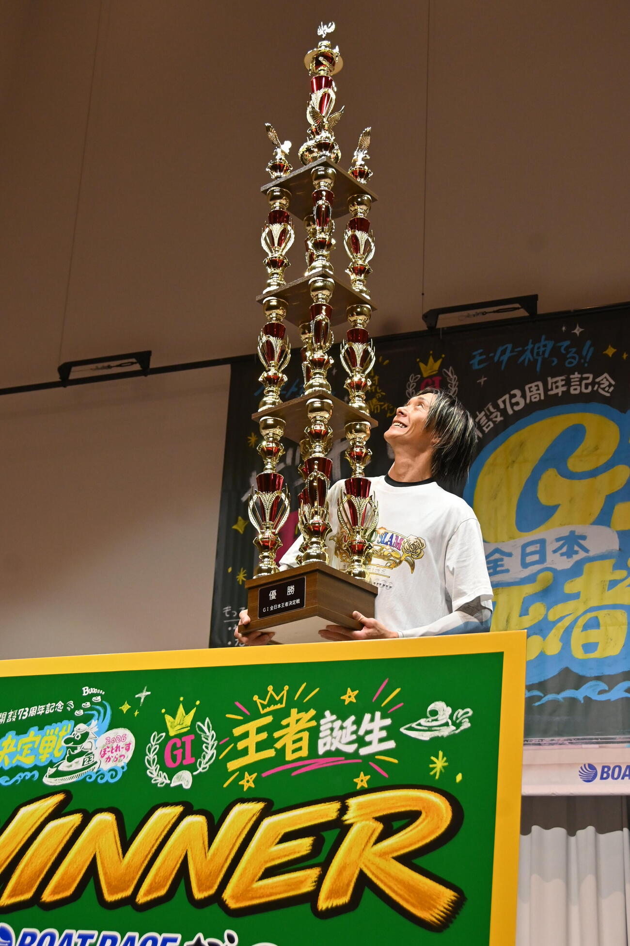 2メートルを超えるトロフィーを見上げる峰竜太