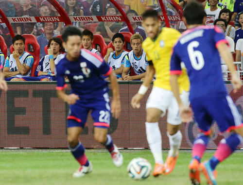 2014年10月14日、日本対ブラジル　前半、ネイマール（手前）のプレーをベンチから見つめる本田（後方右端）ら