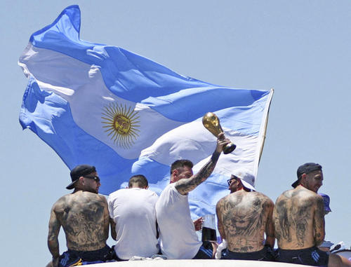 20日、アルゼンチン・ブエノスアイレスの凱旋（がいせん）パレードで、優勝トロフィーを掲げるメッシ選手ら（ロイター＝共同）