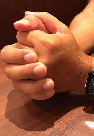 中学教員の佐々木さんは両手を握り、取材に応じた