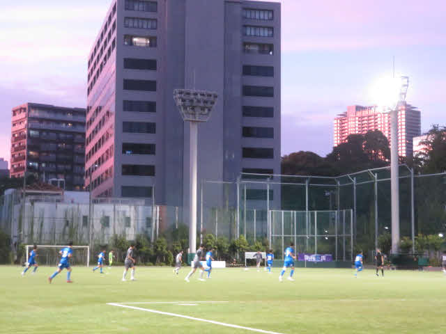 夕焼けが反射するビル群に囲まれたグラウンドで戦う