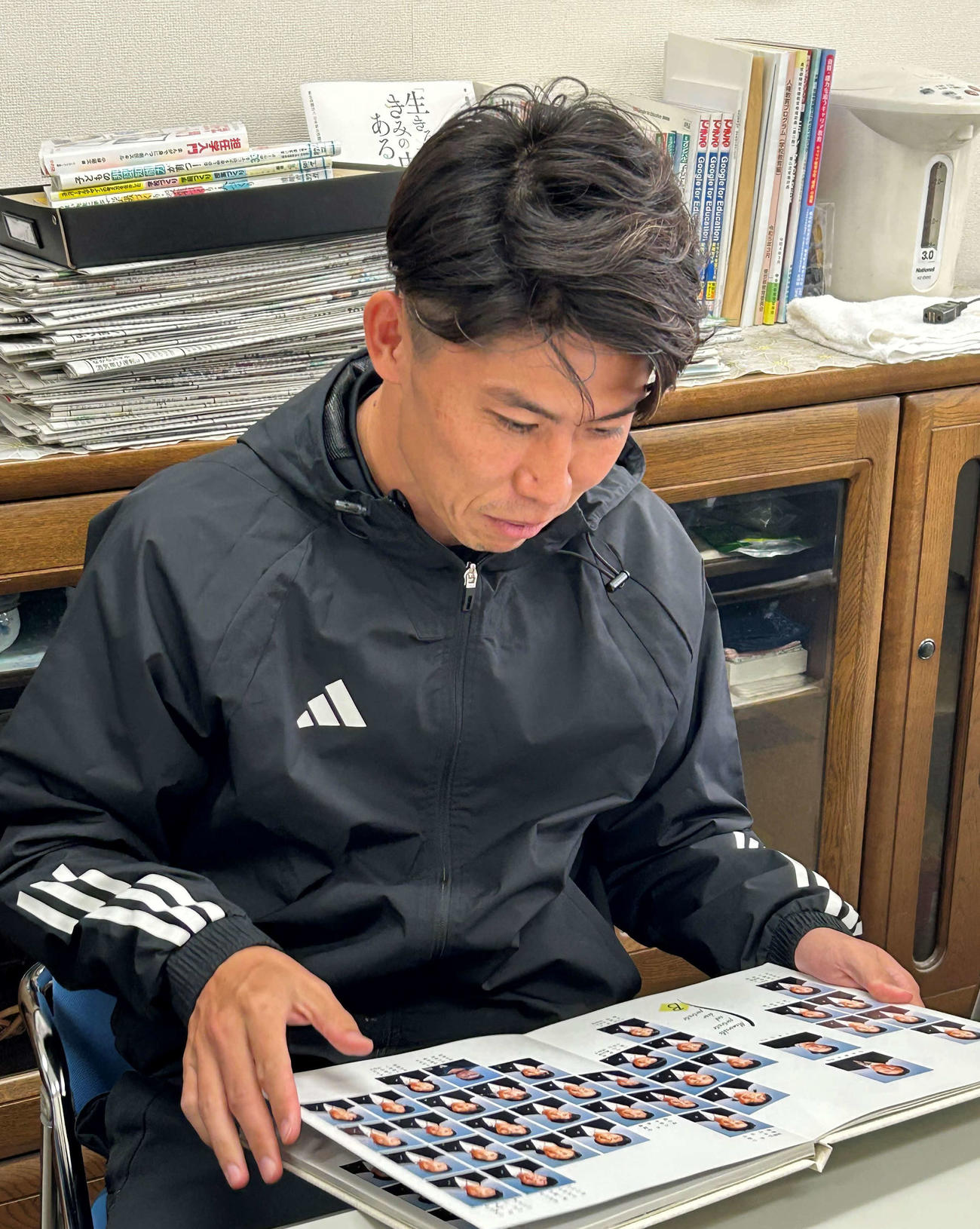 卒業アルバムを見て笑顔になる太田宏介さん