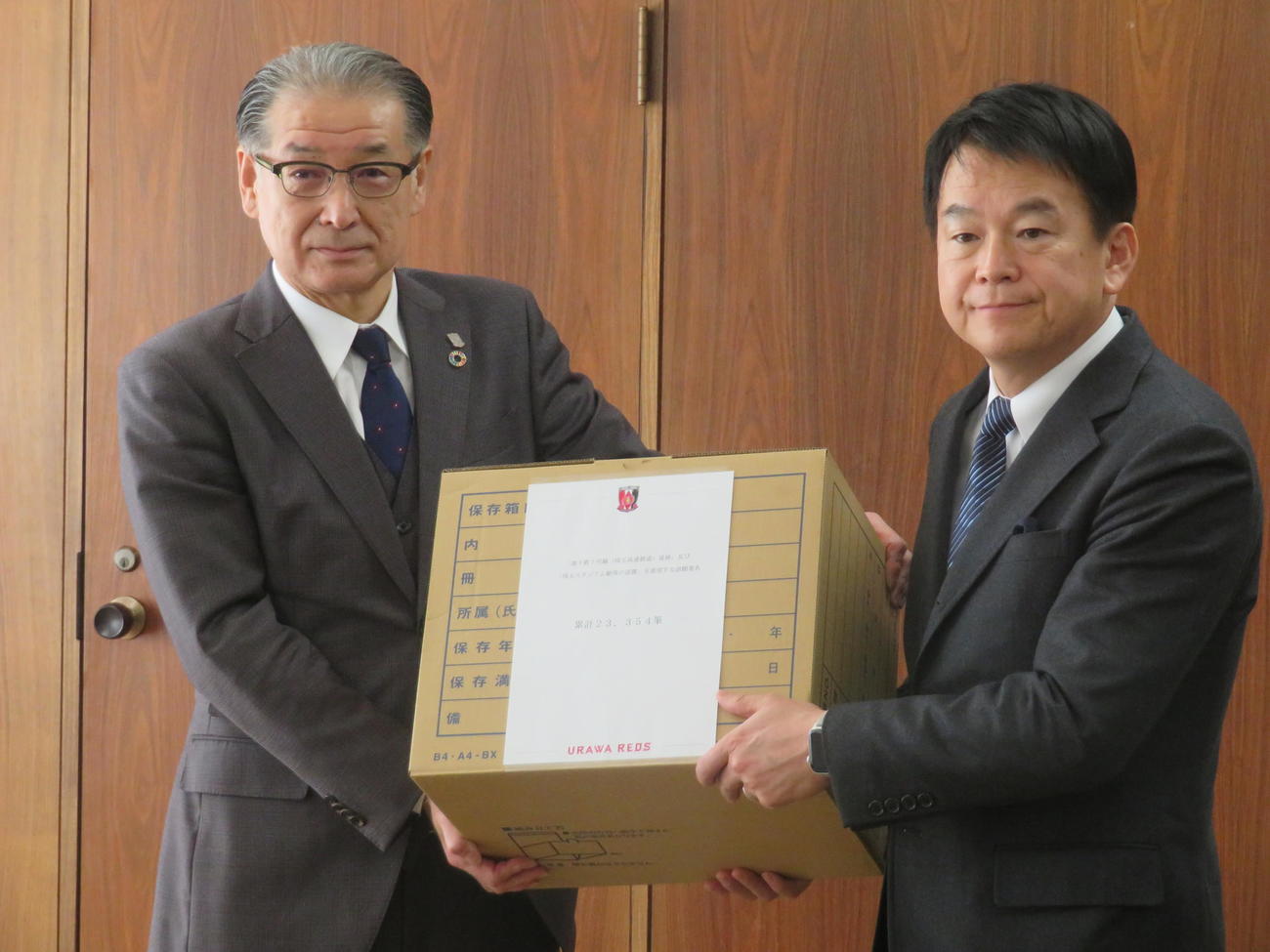 さいたま市の清水市長（右）に2万3000人以上も集まった署名を提出する浦和の立花社長