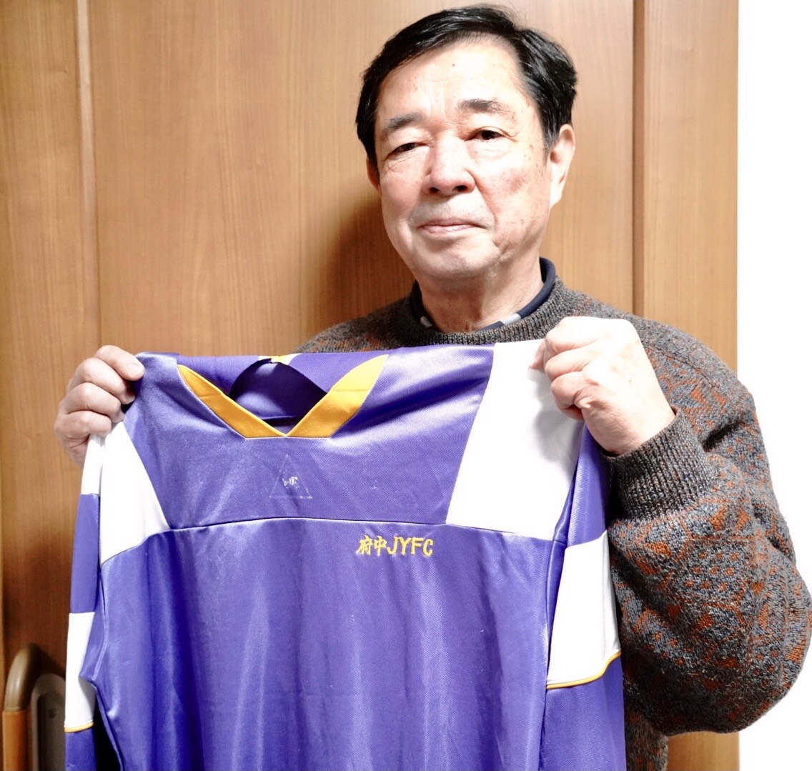 中村憲剛さんの中学時代に所属した府中JYFCのユニホームを手に持つ石川慎二郎さん（撮影・佐藤成）