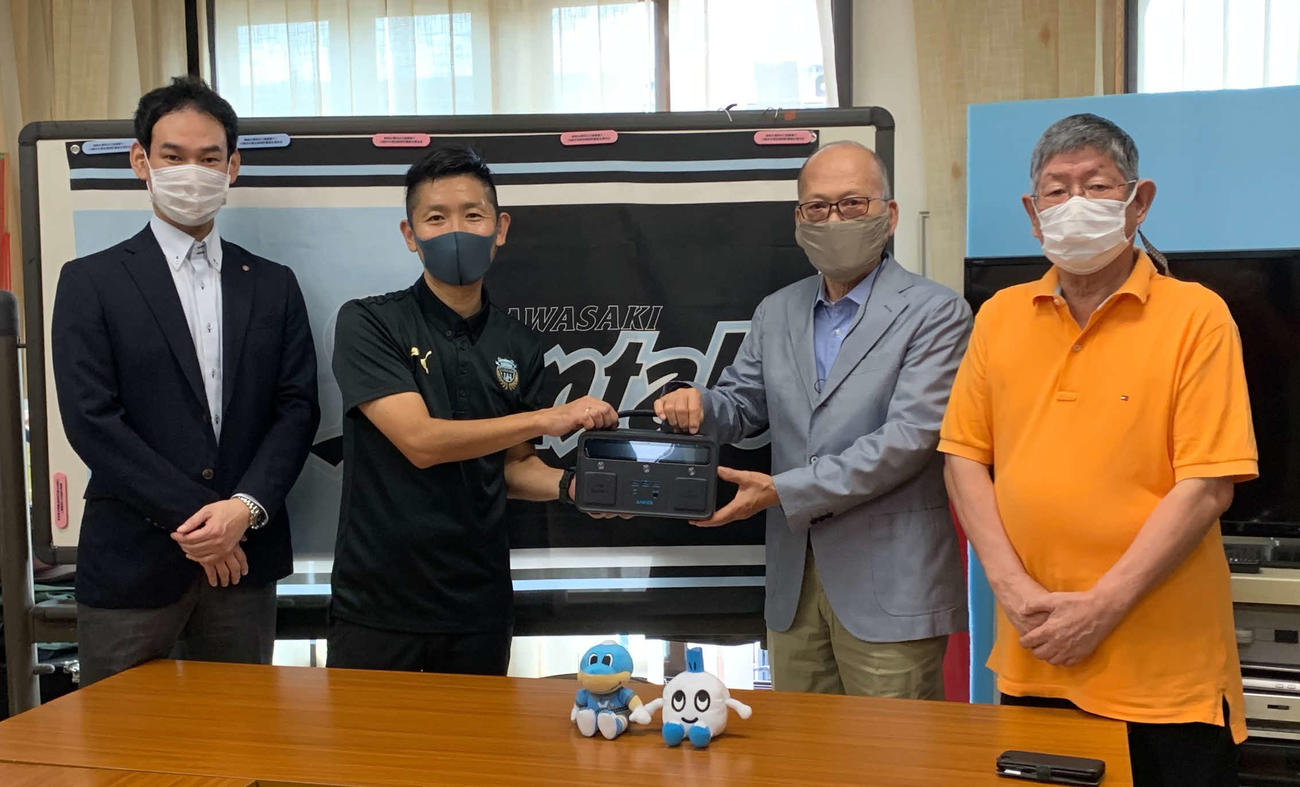 モバイルバッテリーを手に記念撮影する、川崎フロンターレの小林幸太さん（中央左）、川崎市中原区商店街連合会会長の柳沢正高さん（中央右）ら