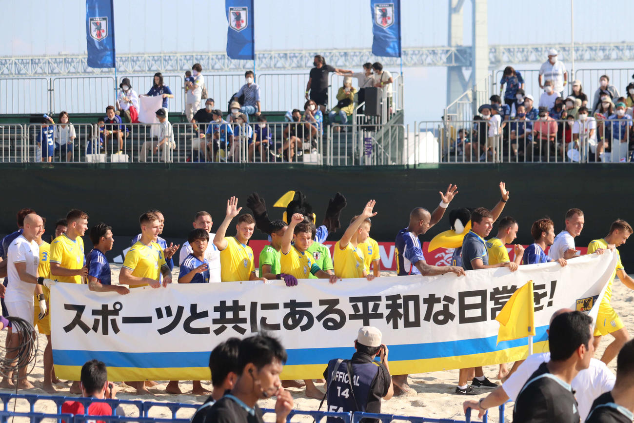 ビーチサッカー国際親善試合の日本－ウクライナで、試合後にフラッグを持ちグラウンドを一周する両チーム（2022年10月1日撮影）