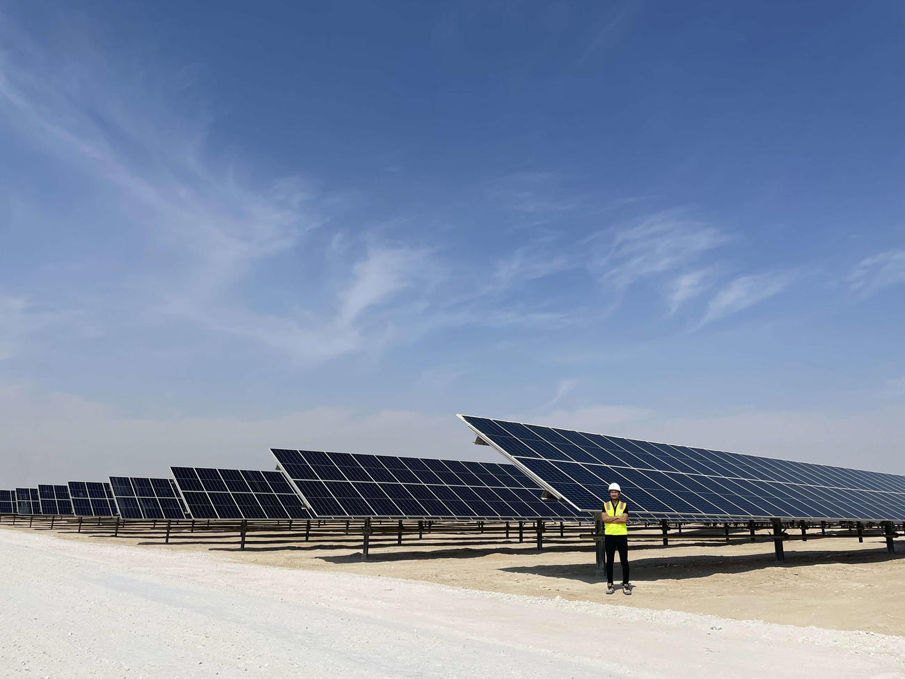 太陽光発電所のパネルの前に立つ河野さん