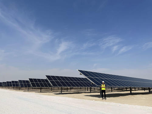太陽光発電所のパネルの前に立つ河野さん