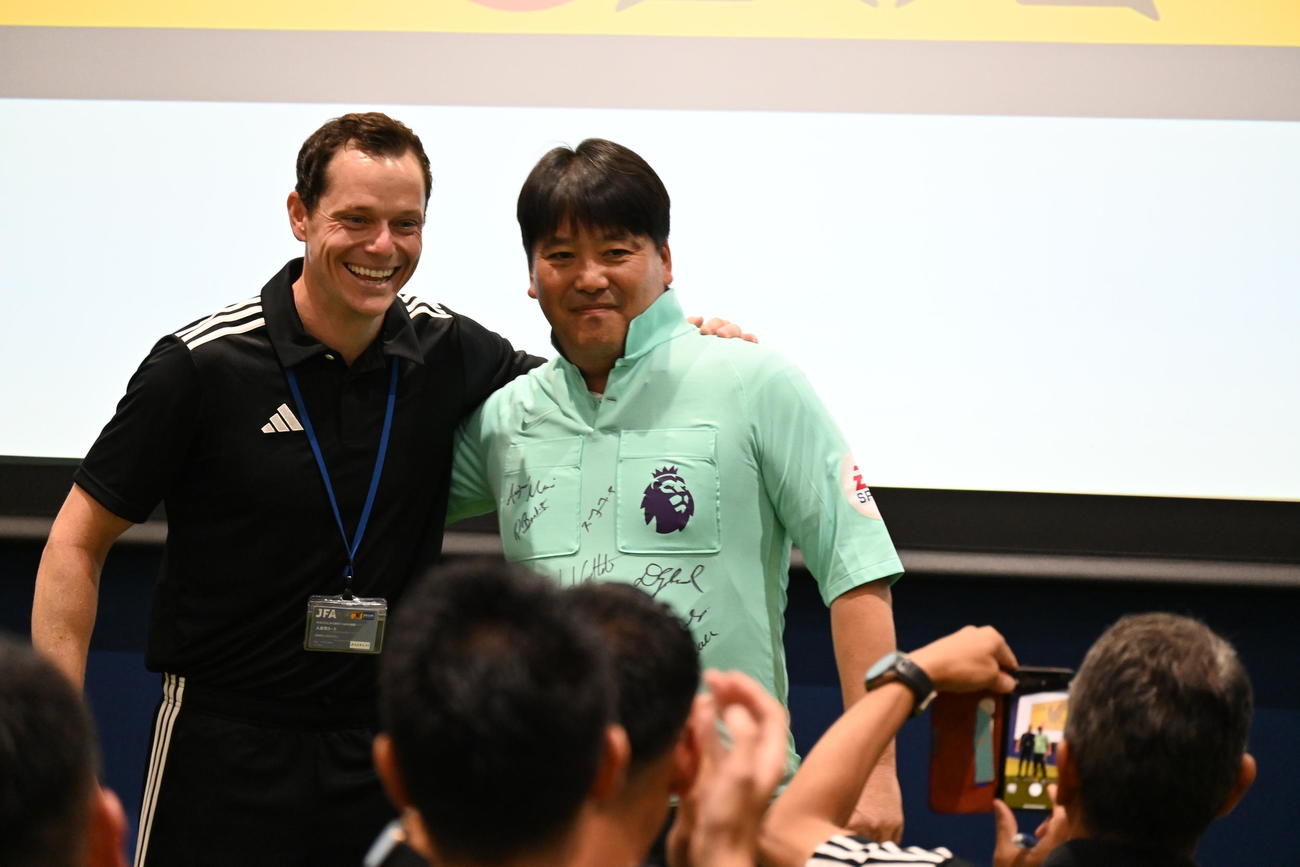 扇谷審判委員長はユニホームを着てイングランド氏と記念撮影（撮影・飯岡大暉）