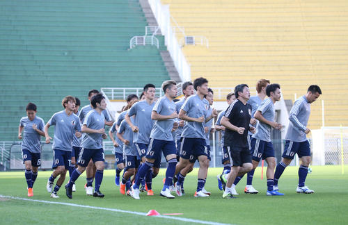 緑と黄色のスタンドを背にランニングする日本代表イレブン（撮影・河野匠）