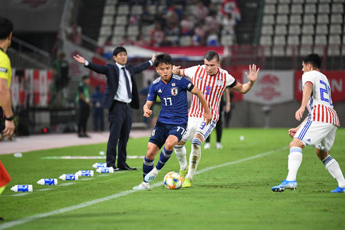 日本対パラグアイ　後半、ライン際を競り合いながらドリブルで攻め込む久保（撮影・加藤諒）