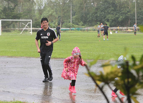 雨の中、レインコートを着て走る子どもを笑顔で見つめる森保監督（撮影・河野匠）