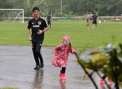 雨の中、レインコートを着て走る子どもを笑顔で見つめる森保監督（撮影・河野匠）