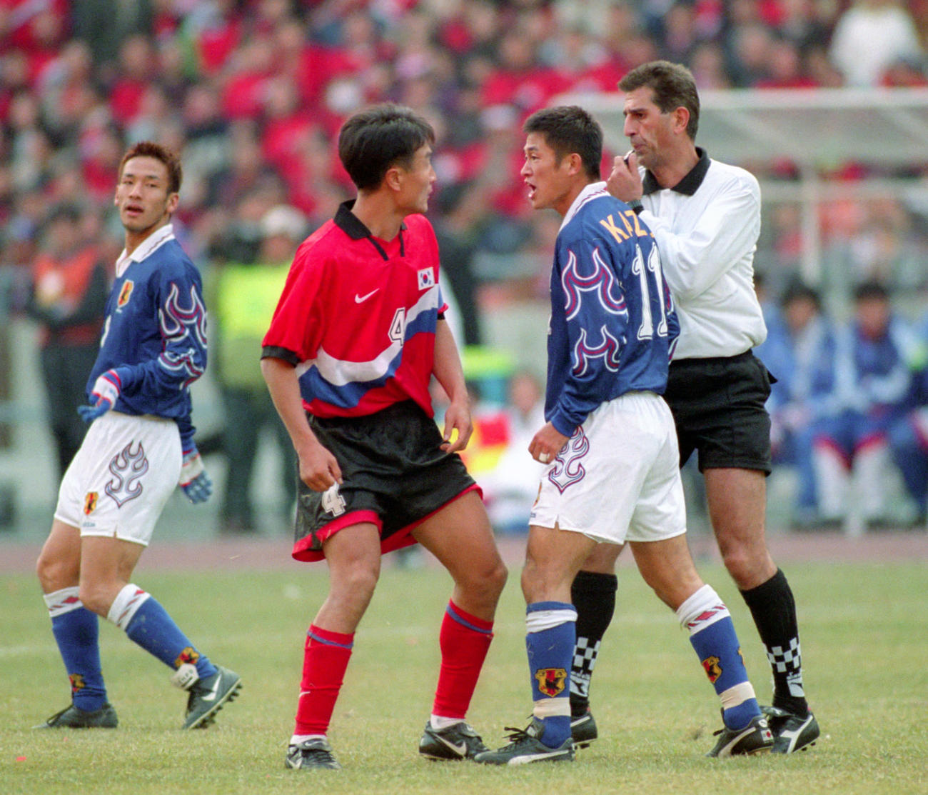 97年11月、W杯アジア最終予選の日本－韓国戦で、韓国DF崔英一(中央）と競り合カズは通算2枚目のイエローカードを受ける。左端は中田英寿