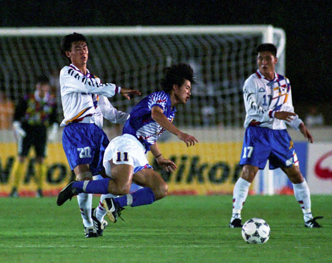 アジア大会決勝トーナメント　日本対韓国　韓国MFホン・ミョンボ（左）に倒されるFWカズ（1994年10月11日）
