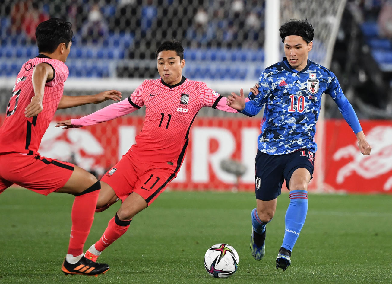 日本対韓国　前半、李洞俊（中央）のマークを受けながらドリブルする南野（右）（撮影・横山健太）
