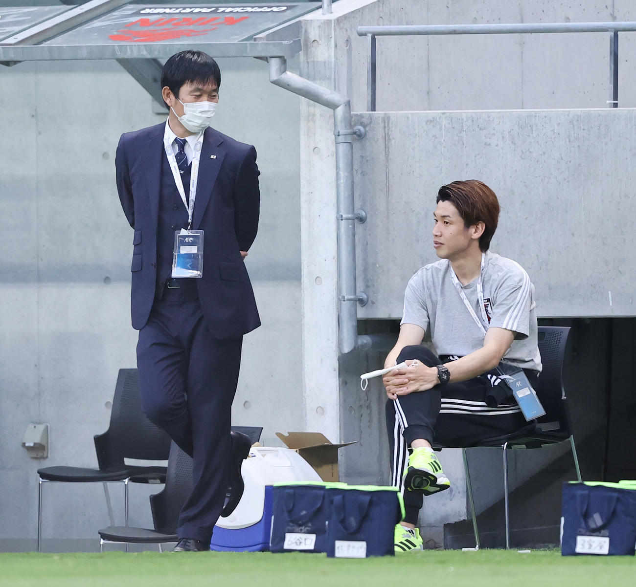 日本対タジキスタン　試合前、ウオーミングアップに参加せずベンチ脇に座る大迫（右）と言葉を交わす森保監督（2021年6月7日撮影）