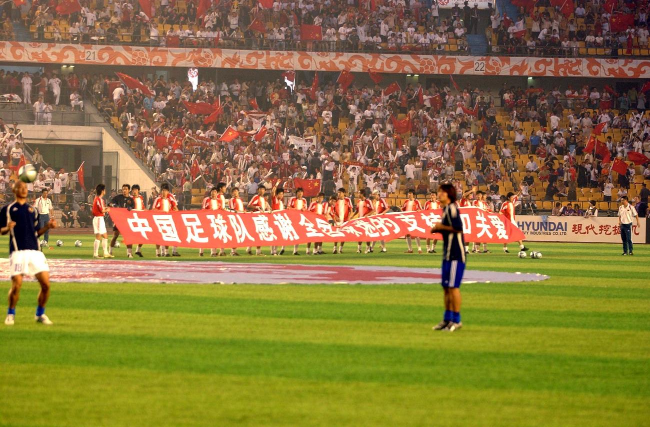 日本対中国の決勝戦直前、観客に自制を呼びかけると思われる横断幕をもって練習に入る中国イレブン（2004年8月7日撮影）