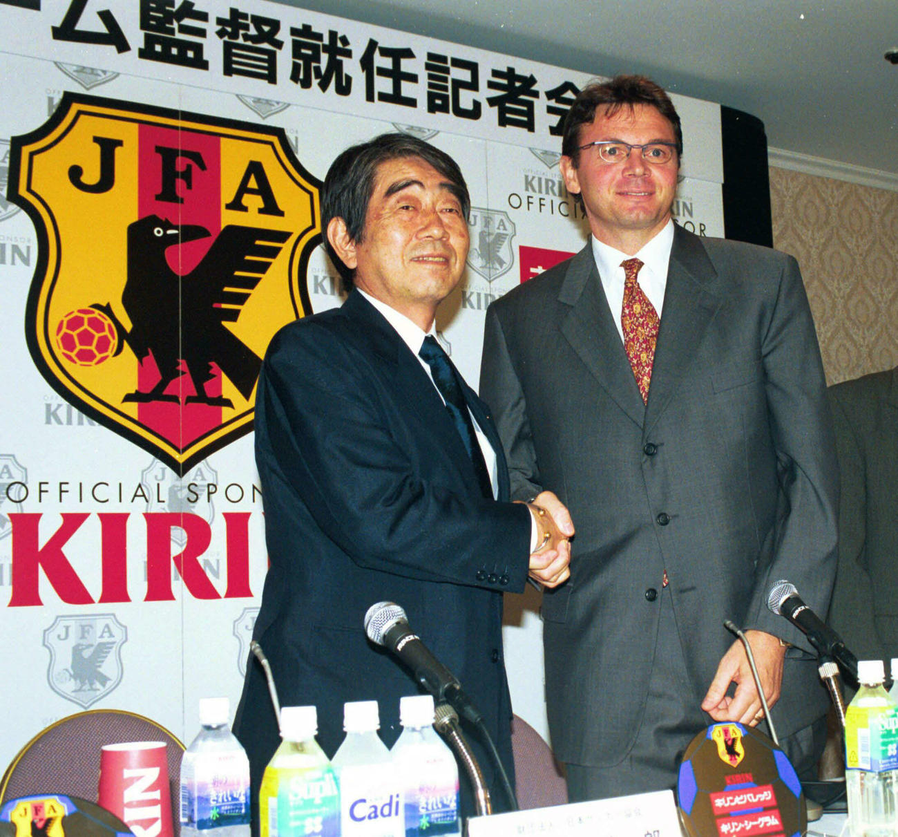 98年9月、日本代表監督に就任し会見を行ったトルシエ監督（中央）は岡野サッカー協会会長とガッチリ握手する