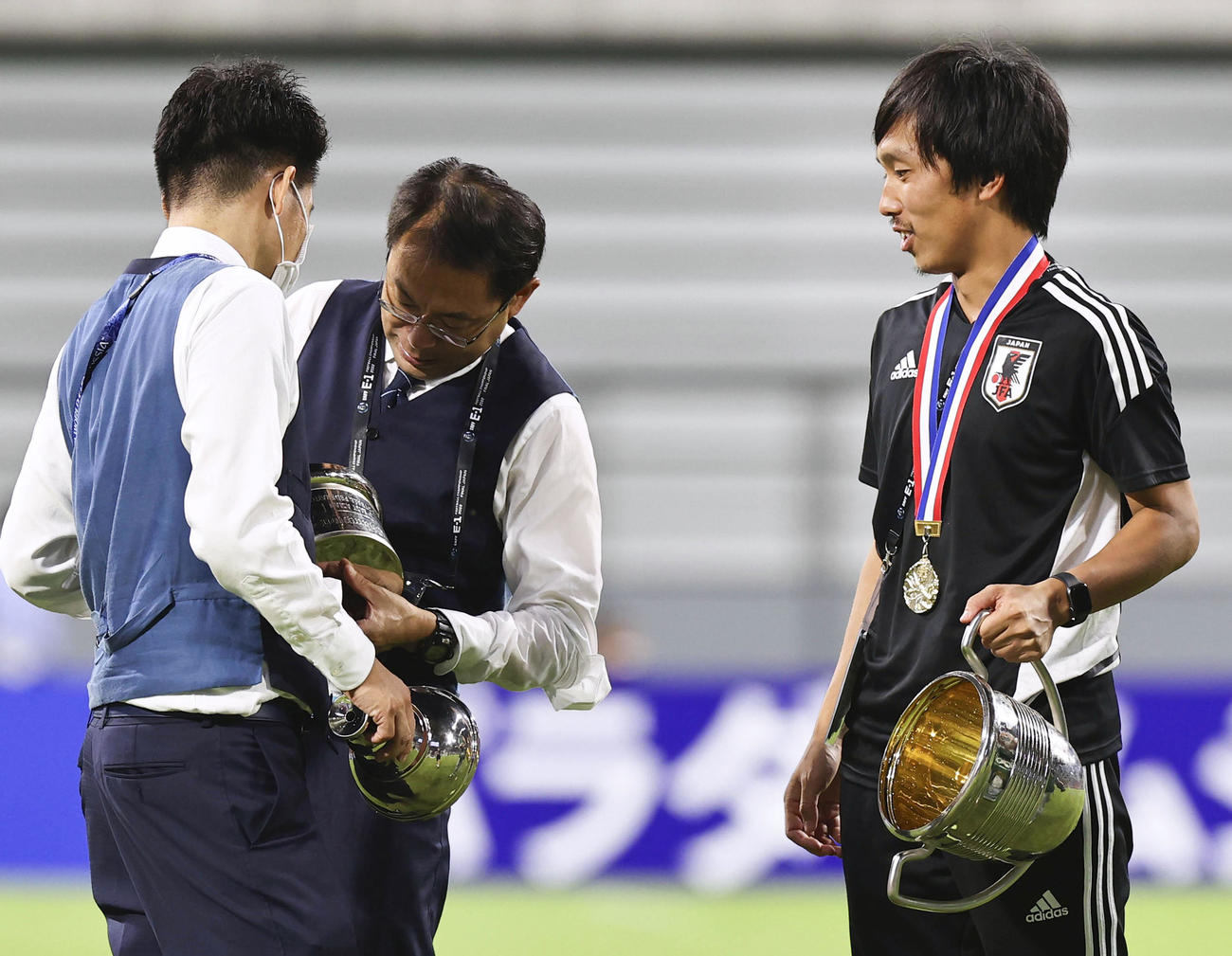 表彰式後、分解したトロフィーを調べる日本サッカー協会の反町技術委員長（中央）ら（共同）
