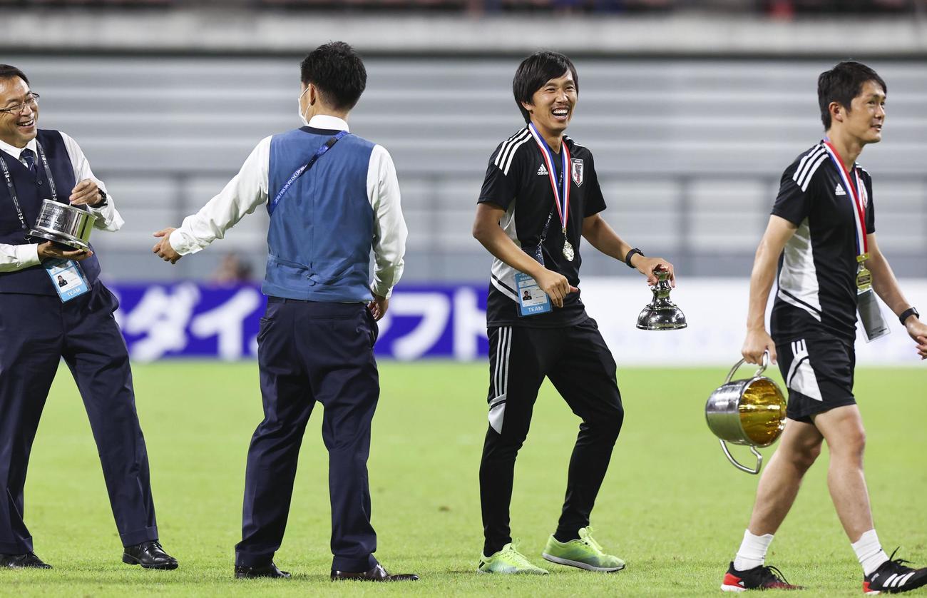 表彰式後、分解したトロフィーを手に苦笑いする日本サッカー協会の反町技術委員長（左端）ら（共同）