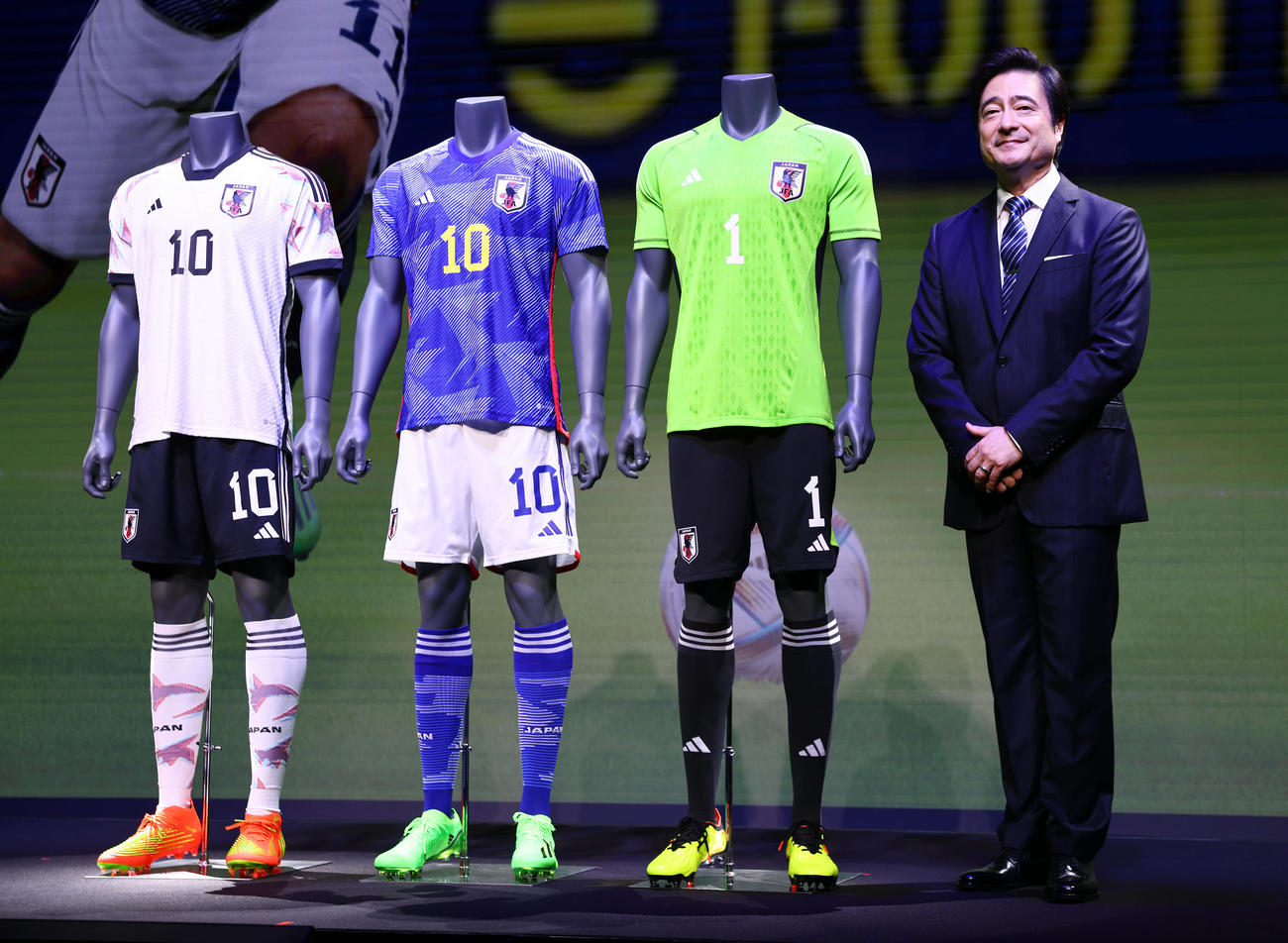 サッカー日本代表新ユニホーム発表会見で日本代表の新ユニホームと写真に納まるジョン・カビラ氏（撮影・垰建太）