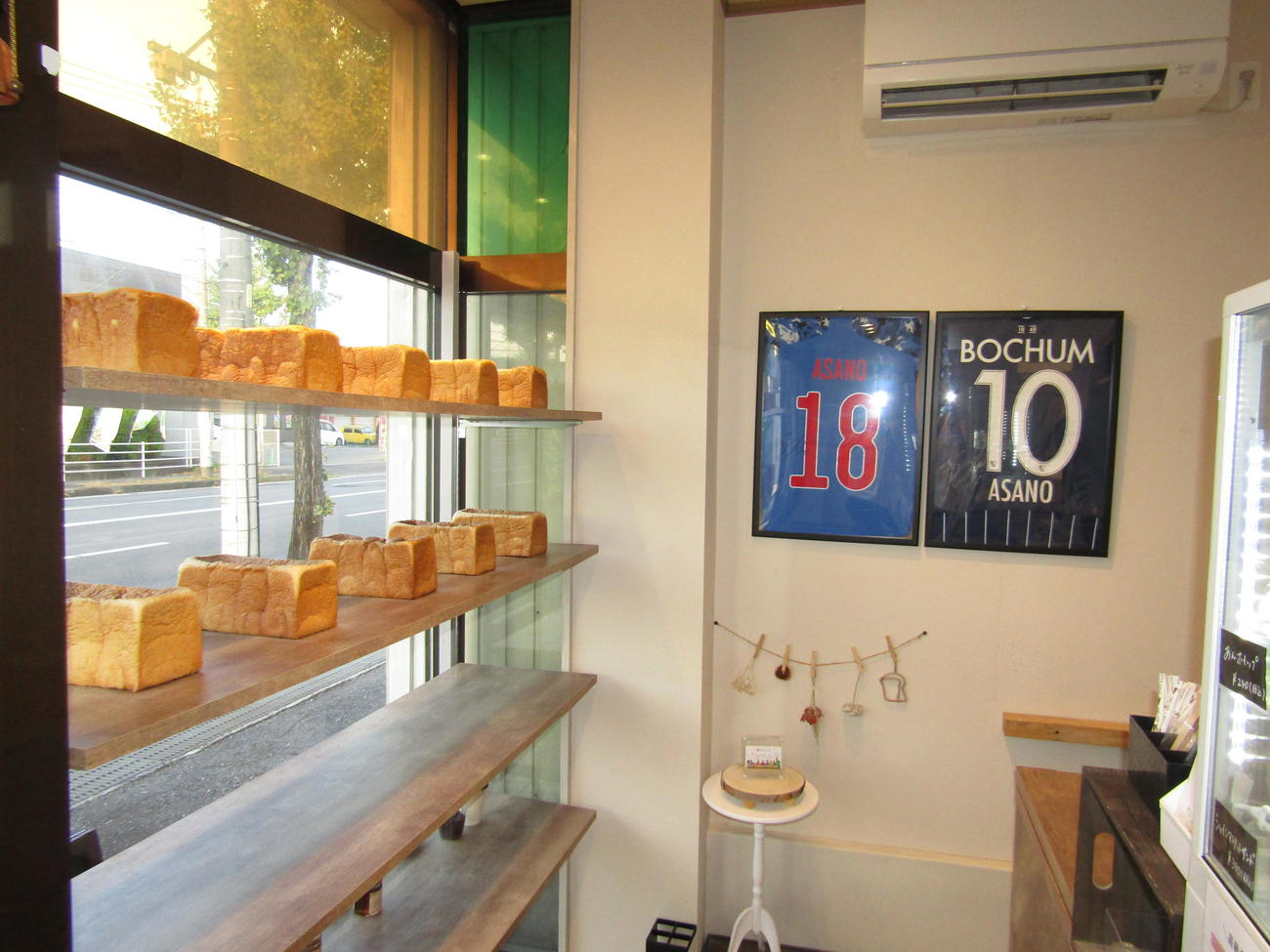 浅野拓磨が経営する食パン店「朝のらしさ」の店内には、おいしそうな食パンとともにユニホームも掲示されている