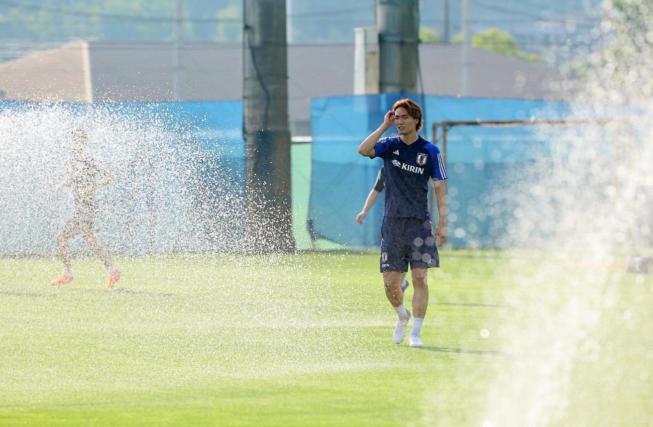 スプリンクラーの水の間を通りグラウンドに入る板倉（撮影・上田博志）