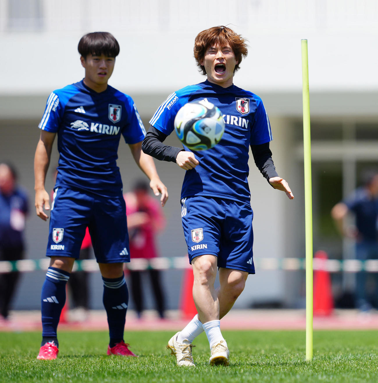 練習中、パスを出しておどけた表情を見せる古橋（右）。左は川崎（2023年6月16日撮影）