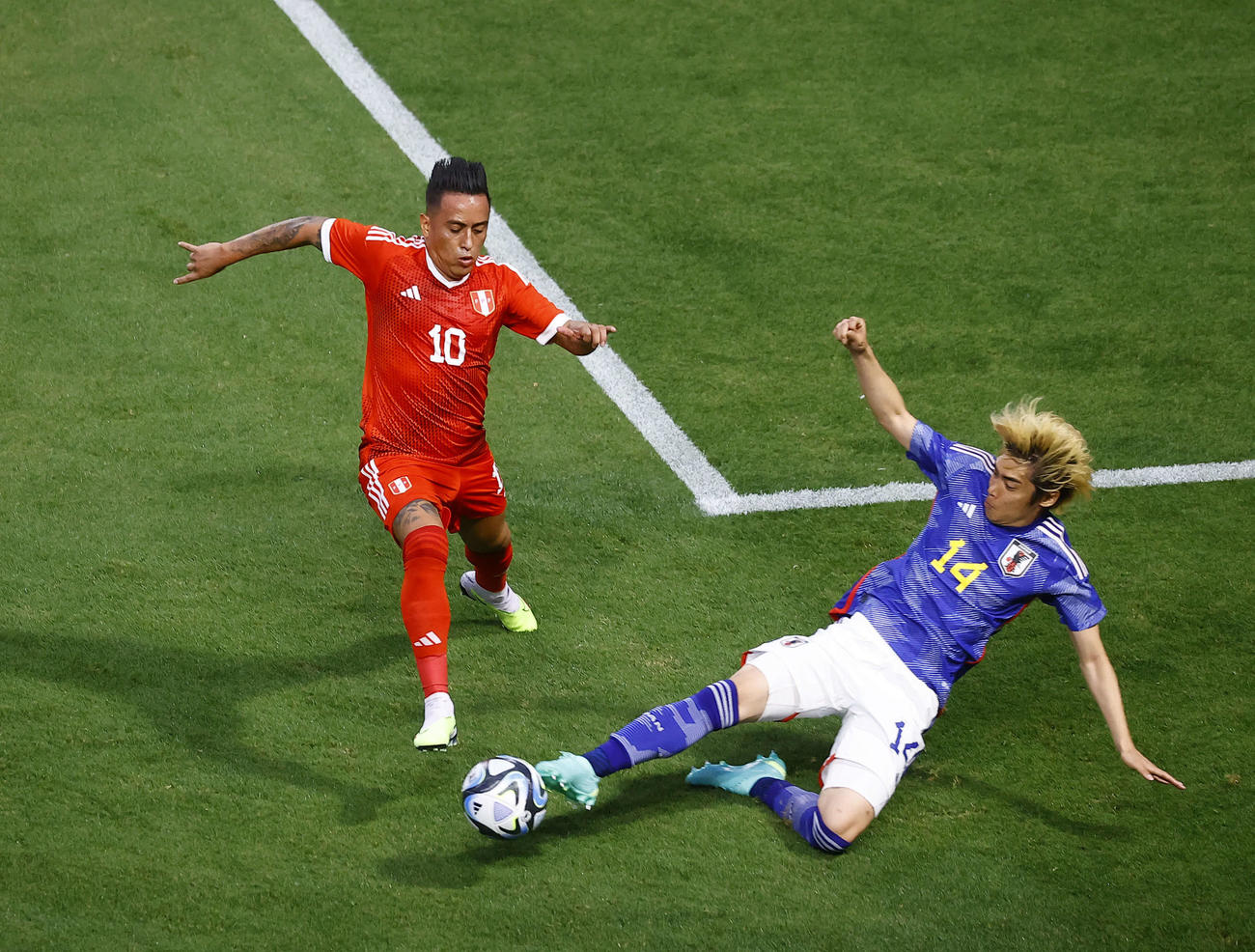 日本対ペルー　前半、スライディングでボールを奪う伊東。左はクエバ（撮影・藤尾明華）