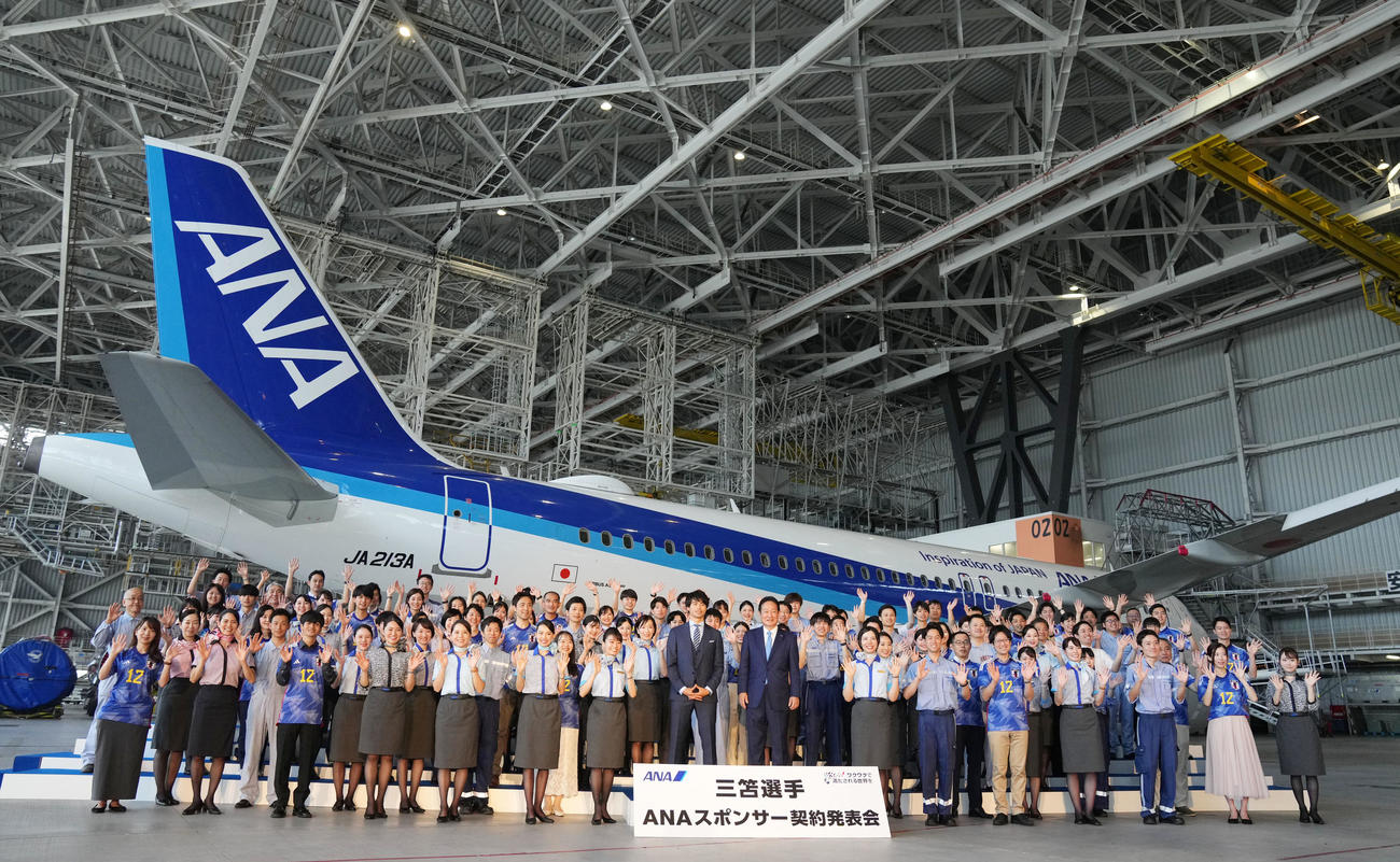 航空機を背にANAスタッフと笑顔を見せる三笘（中央）（撮影・横山健太）