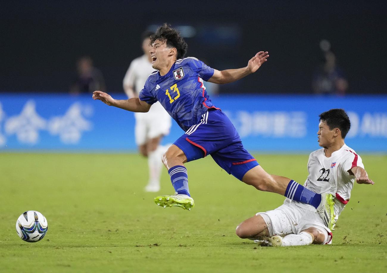 日本―北朝鮮　後半、タックルを受け倒される佐藤（左）＝杭州（共同）
