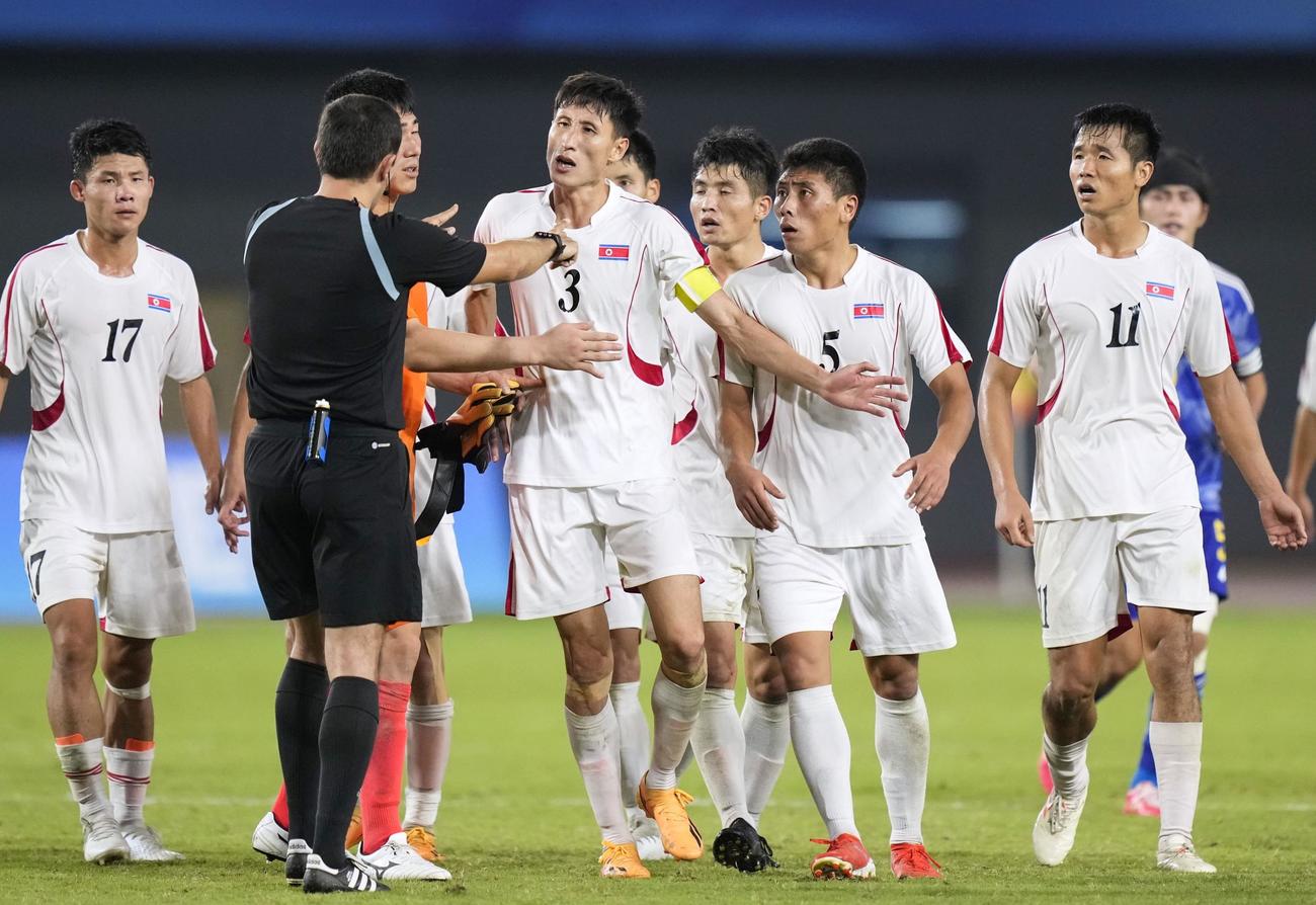日本に敗れ、試合終了後に審判に詰め寄る北朝鮮の選手＝杭州（共同）