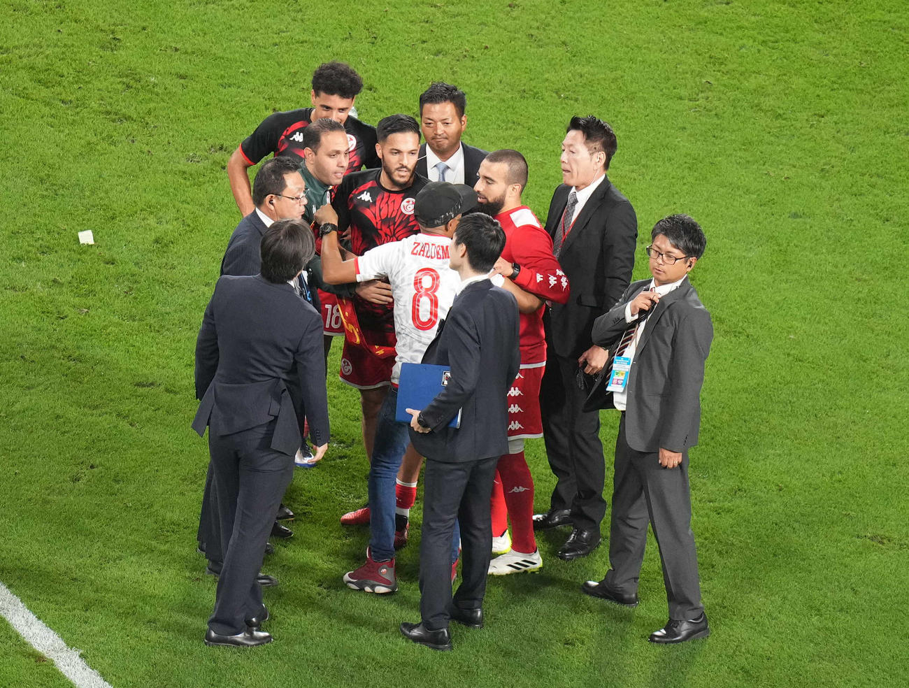 日本対チュニジア　試合後、ピッチに乱入したサポーター（手前）にスタッフが取り囲む中、話を聞くチュニジア代表スリティ（右）（撮影・狩俣裕三）