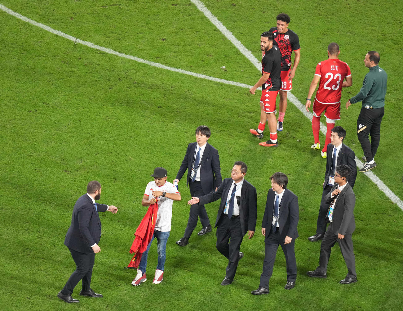 日本対チュニジア　試合後、ピッチに乱入したサポーター（手前）は、チュニジア代表スリティ（後方右から2人目）から練習着をもらい満足そうに引き揚げる（撮影・狩俣裕三）