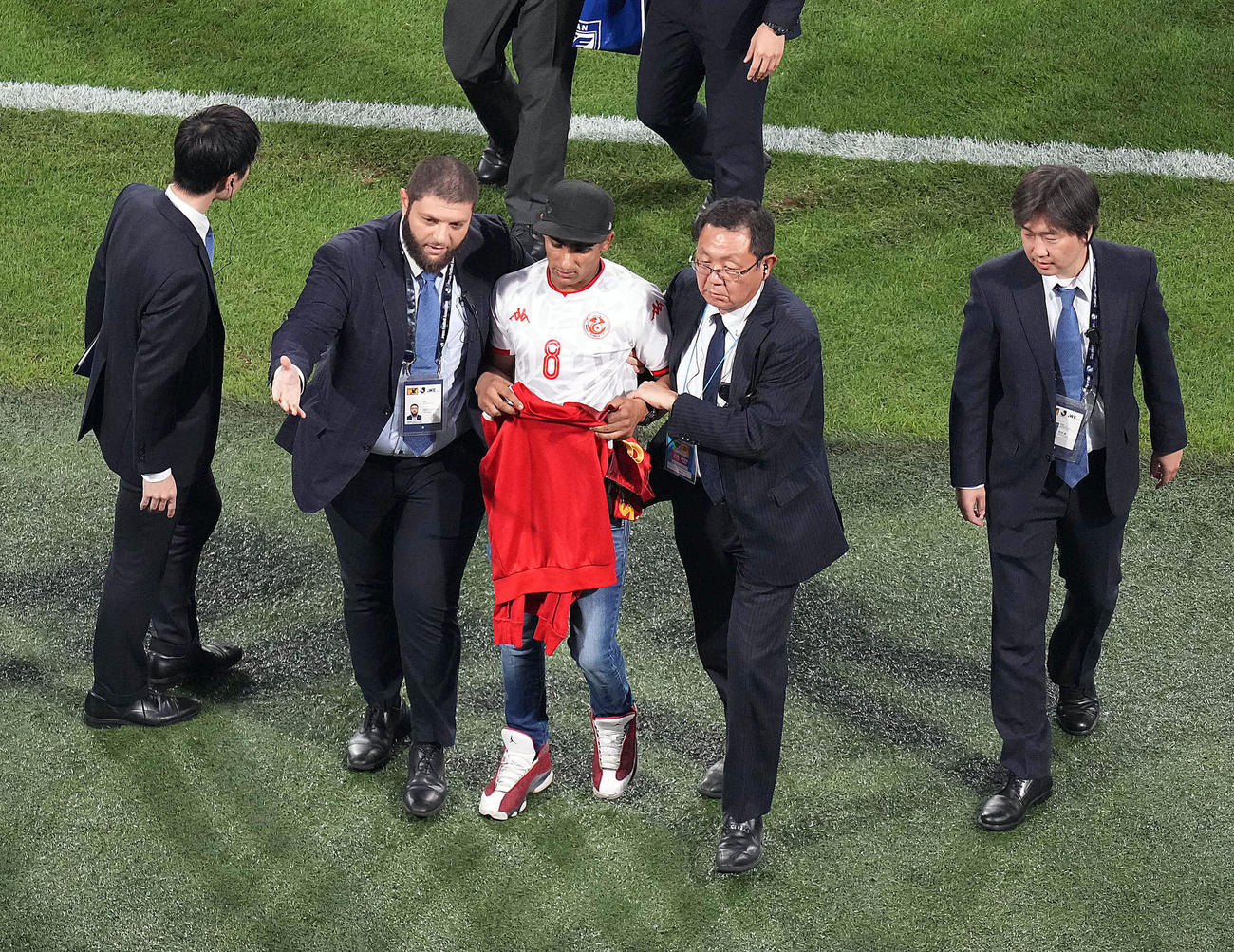 日本対チュニジア　試合後、ピッチに乱入したサポーター（中央）は、チュニジア代表スリティからもらった練習着を手にスタッフに連行される（撮影・狩俣裕三）