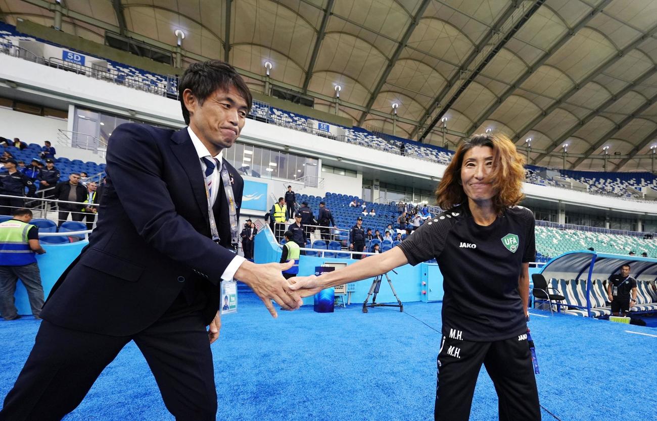 試合前、ウズベキスタンの本田監督（右）と握手を交わす日本の池田監督（共同）