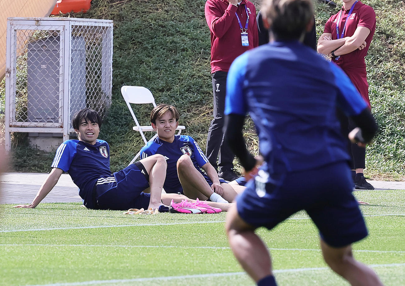 リラックスした表情で練習を見つめる三笘（左）と久保（撮影・足立雅史）