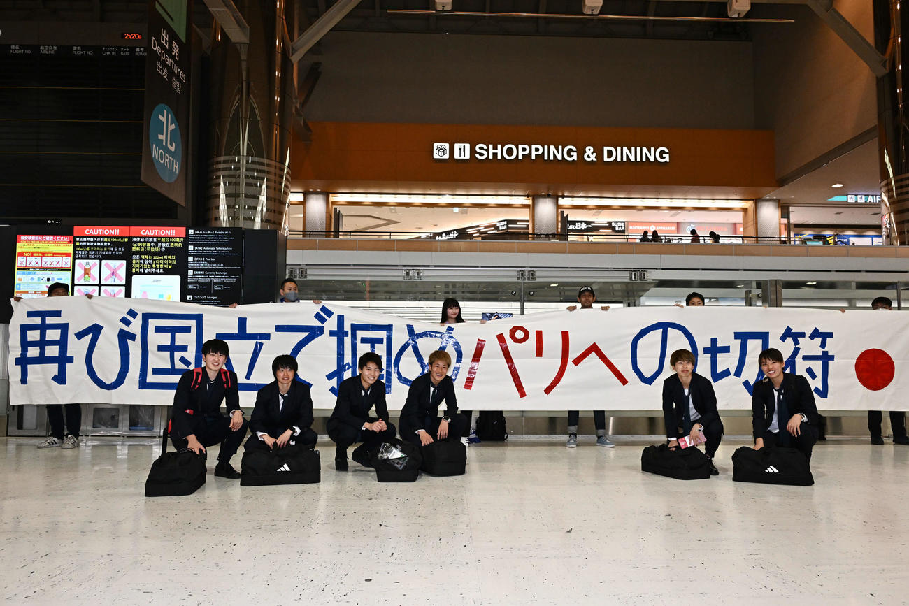 成田空港からサウジアラビアのジッダへ出発するなでしこジャパンの選手たちは、サポーターの横断幕を背に記念撮影する。左から古賀、上野、清家、GK平尾、田中美、熊谷（撮影・滝沢徹郎）