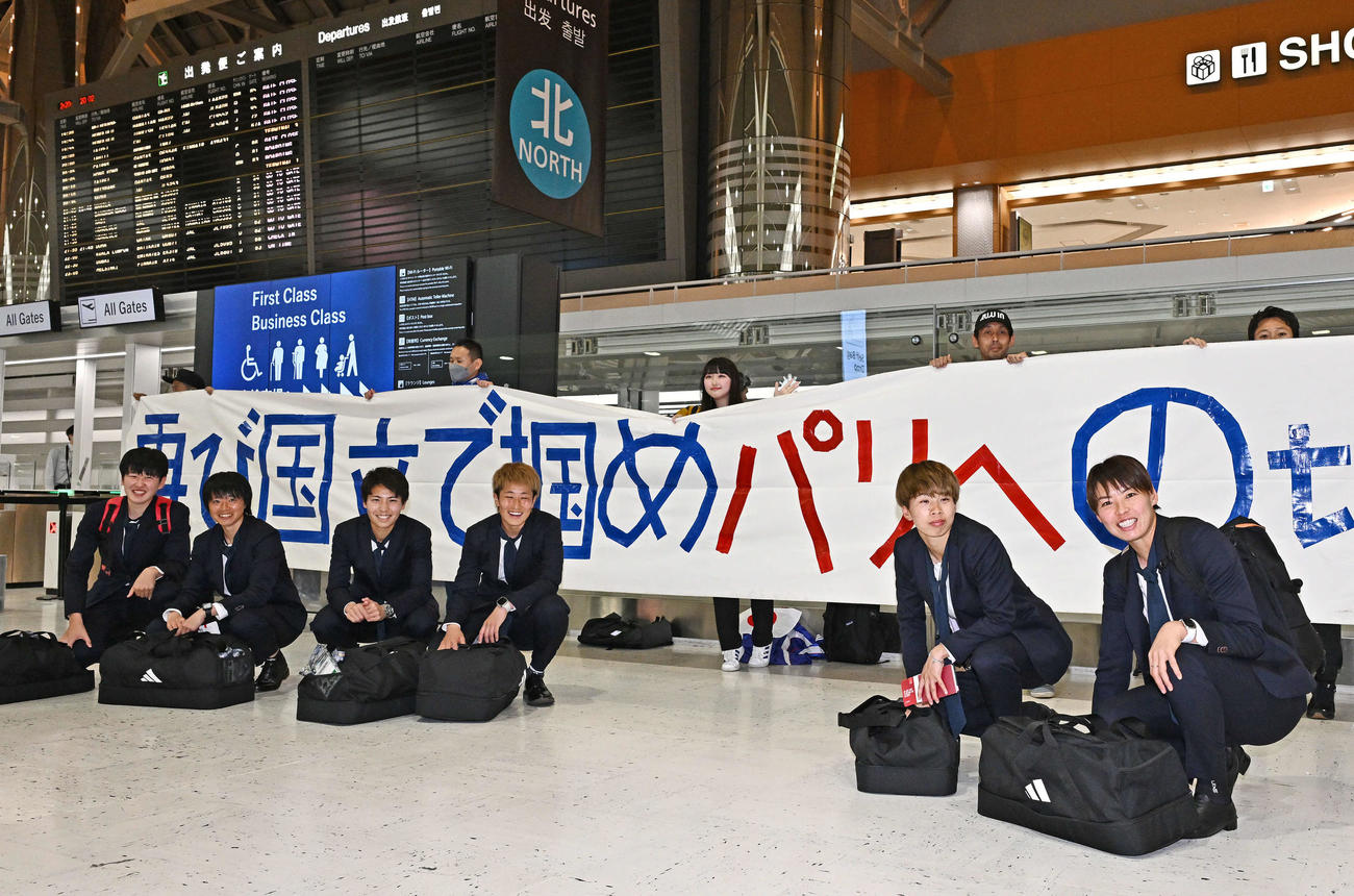 成田空港からサウジアラビアのジッダへ出発する、なでしこジャパン熊谷（右）らはサポーターの横断幕を背に記念撮影する。左から古賀、上野、清家、GK平尾、田中美（撮影・滝沢徹郎）