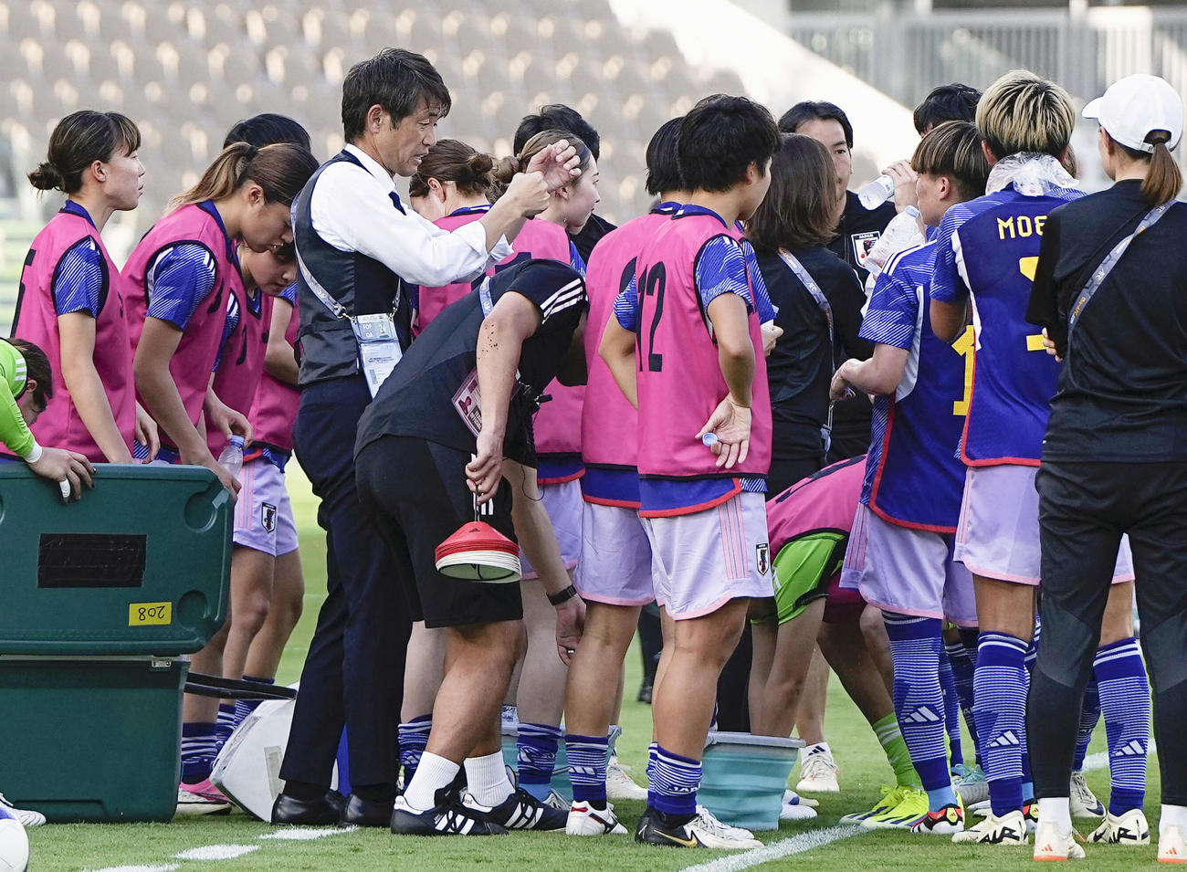 　前半、給水する選手に指示を出す池田監督（左から3人目）（共同）