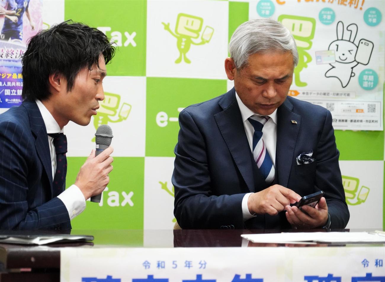 国税庁の確定申告イベントで、担当者から説明を受けながらスマートフォンを操作する日本サッカー協会佐々木則夫女子委員長（右）（撮影・佐藤成）