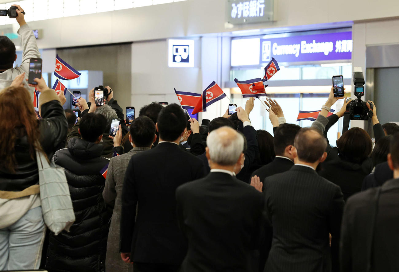 2月25日、国旗を振りサッカー女子北朝鮮代表を迎える関係者（撮影・鈴木正人）
