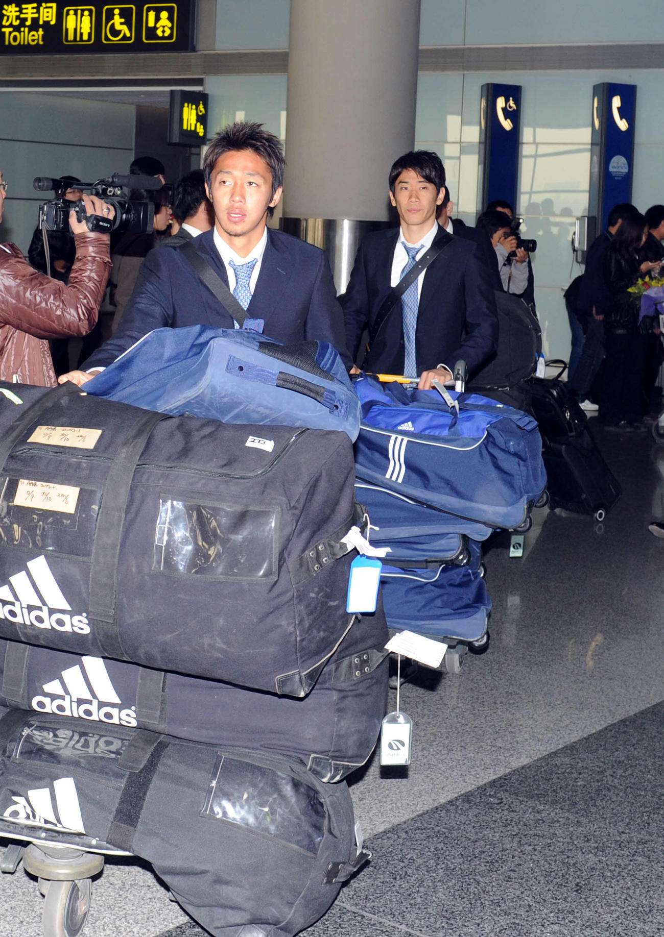 2011年11月16日　平壌から経由地の北京に到着し、大量の荷物を運ぶ清武（左）と香川