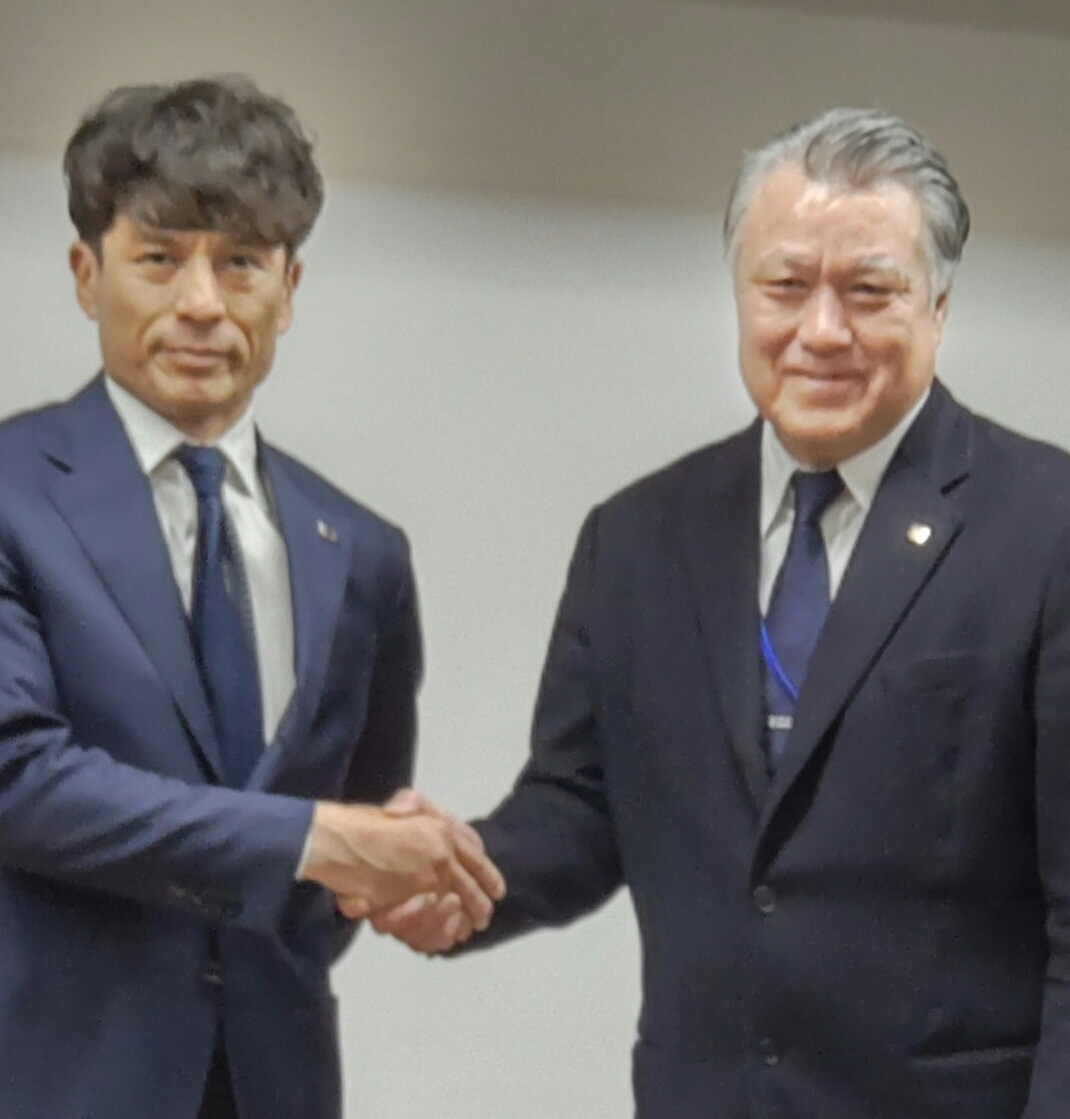 田嶋前会長（左）と握手をする新会長の宮本氏