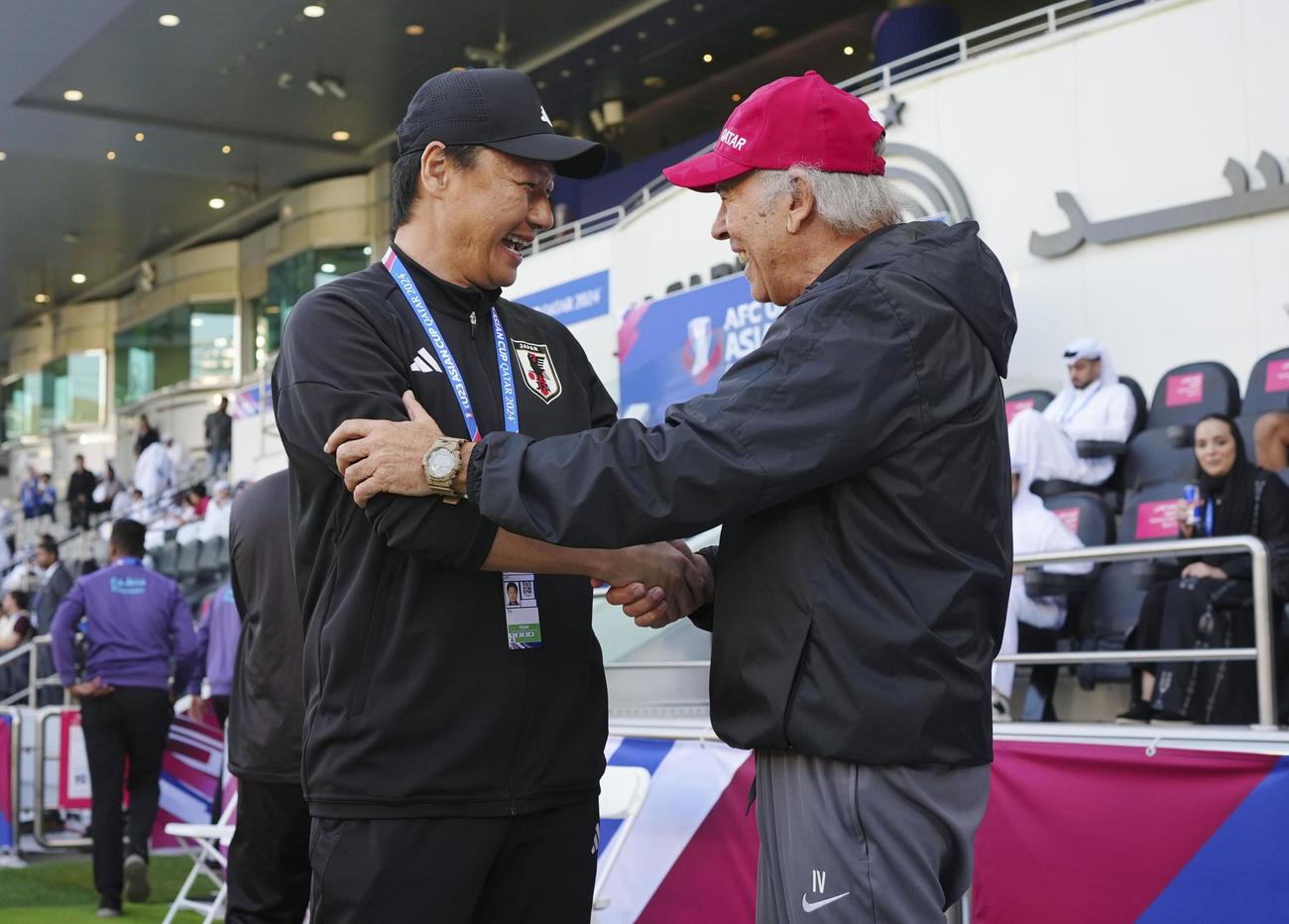 試合開始前、カタールのバレ監督（右）と握手を交わす大岩監督＝ドーハ（共同）