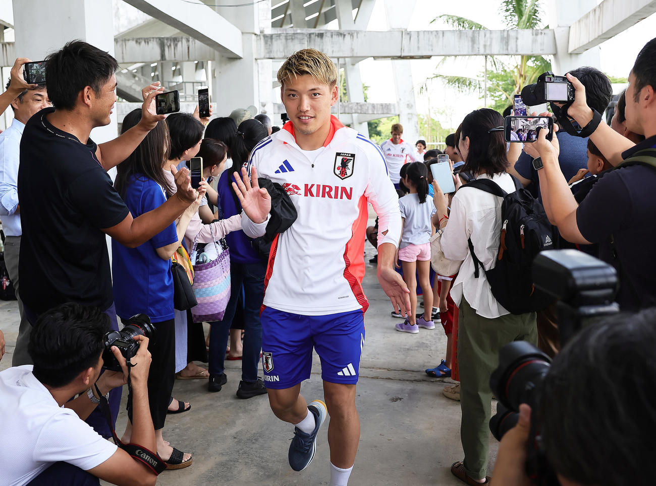 ミャンマーに到着し、現地日本人ファンとタッチを交わし練習に臨む堂安（撮影・足立雅史）