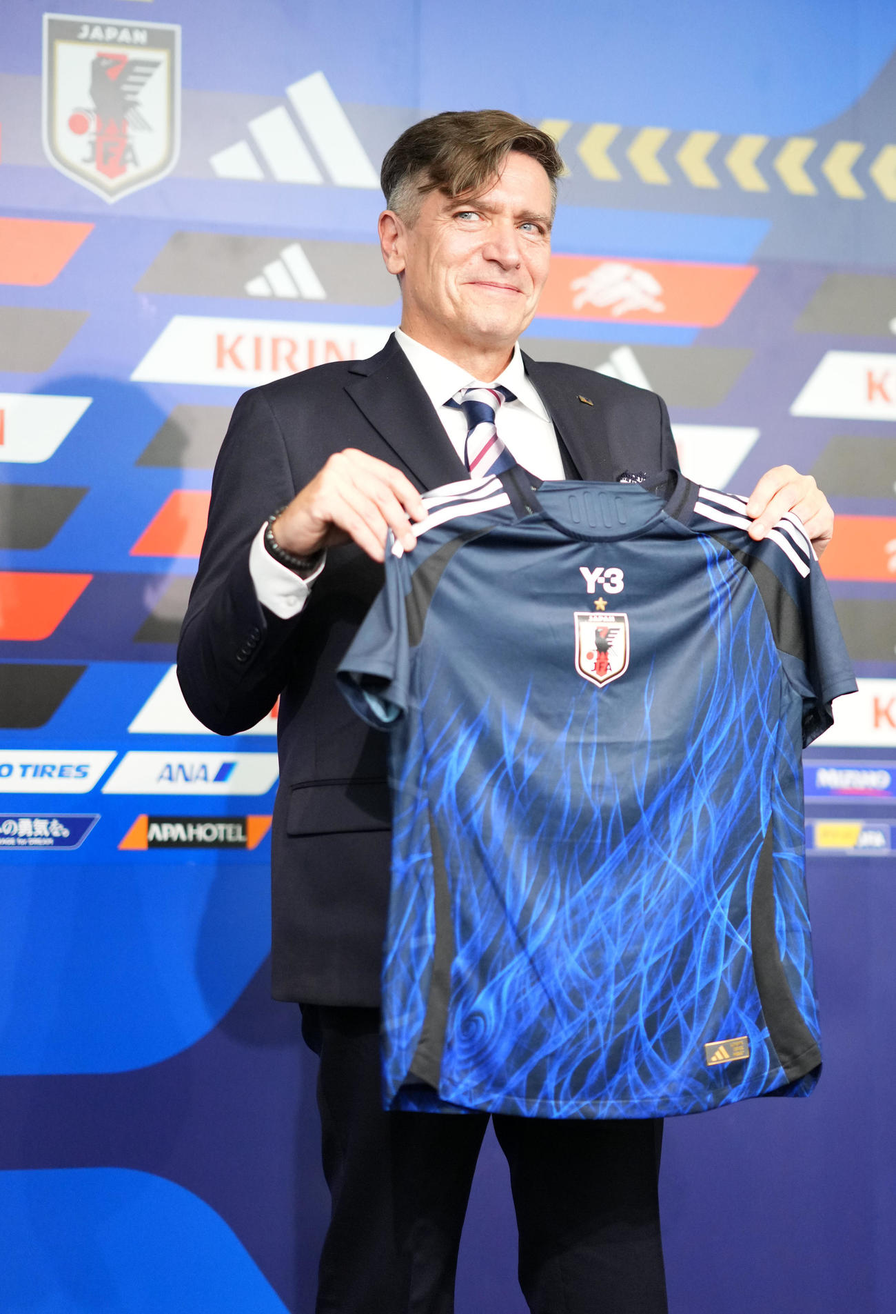 ユニホームを手に笑顔をみせるニルス・ニールセン新監督（撮影・横山健太）