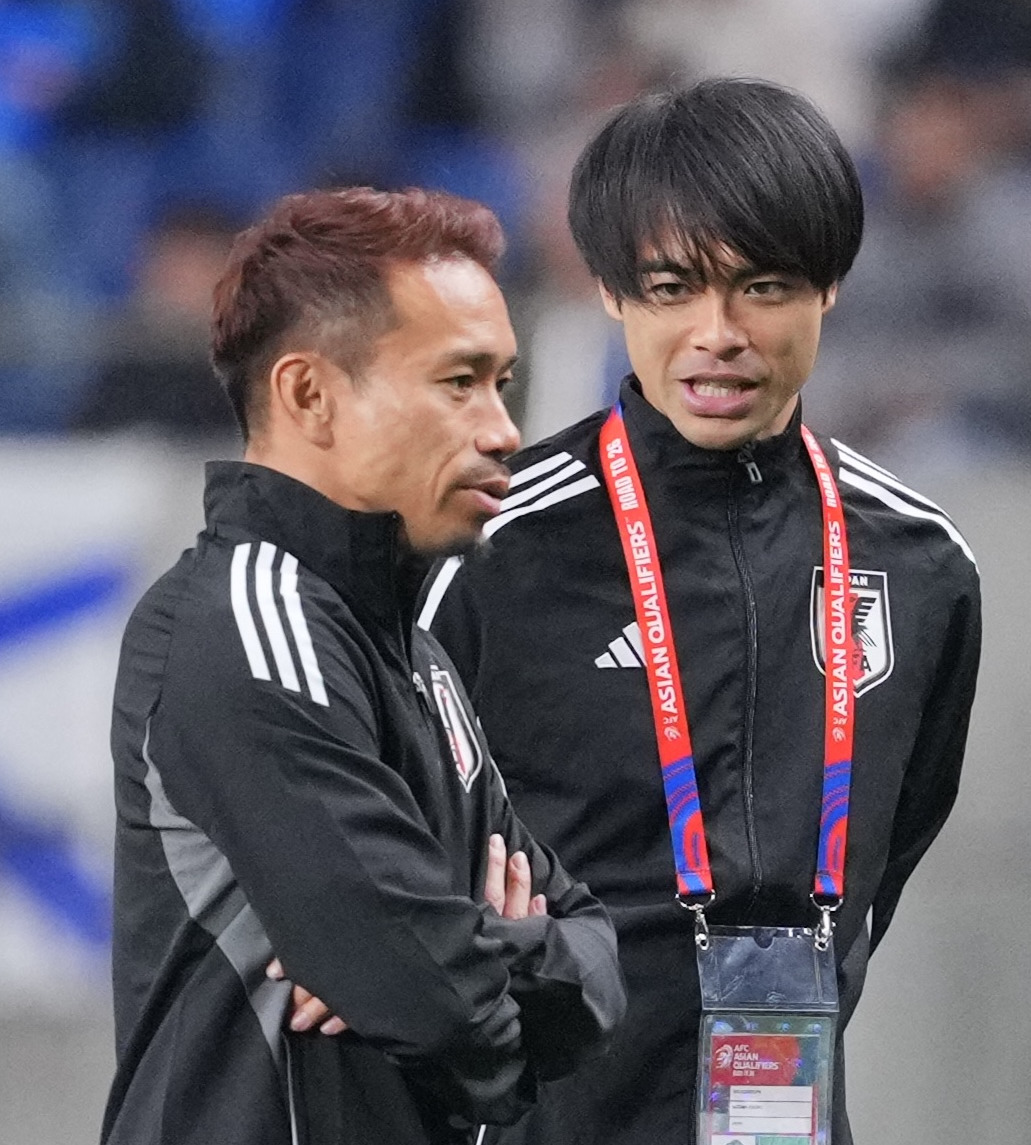 日本対サウジアラビアの試合前、選手たちの練習を見つめる三笘（右）と長友＝25年3月